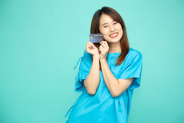 Portrait of young Asian woman in blue patient suit holding credit card isolated on green background