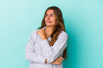 Fototapeta premium Young caucasian woman isolated on blue background confused, feels doubtful and unsure.