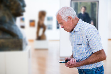 mature European man examines sculpture in an exhibition in hall of an art museum
