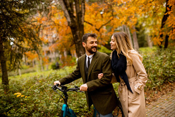 Fototapeta premium Young couple in the autumn park with electrical bicycle