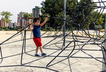 child walking on top of rope pyramid in playground