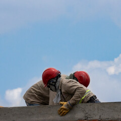 Men working in the heights with sky in the background.