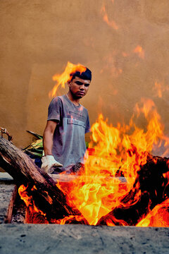 Young man cooking agave leaves on a fire pit for traditional Mexican barbecue