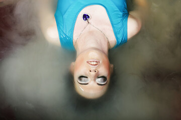 Fototapeta premium Attractive woman with closed eyes takes a milk bath. Bright makeup, blue dress, fantasy style.