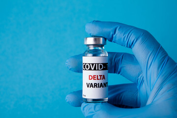 Female doctor holding syringe and COVID-19 delta variant vaccine isolated on blue background. Healthcare And Medical concept.