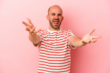 Young caucasian bald man isolated on pink background  feels confident giving a hug to the camera.