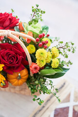 Part of a basket with beautiful autumn flowers made of red roses, sunflowers and green leaves, with barberry berries. The concept of the holiday. Copy space. High quality photo