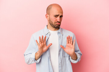 Young caucasian bald man isolated on pink background  rejecting someone showing a gesture of...