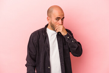 Young caucasian bald man isolated on pink background  covering mouth with hands looking worried.