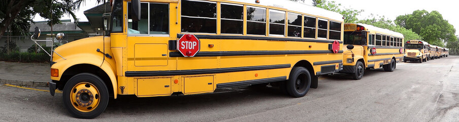 Long line of yellow school buses waiting to pick up students at the end of the school day. 