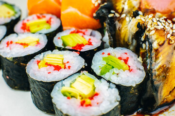 Tasty Colorful assorted Set of different type Sushi. Dinner in Japanese style. Healthy food. Filadelfia and Maki sushi rolls with Avocado, Tuna, Salmon, fish and Prawns. Close up view. Wallpaper.
