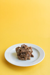 Canned beef stew on white plate with parsley leaf, yellow background