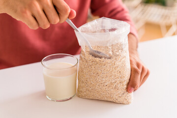 Young mixed race man eating oatmeal and milk for breakfast in his kitchen