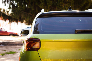 Back window of green car parked on the street in summer sunny day, rear view. Mock-up for sticker or decals