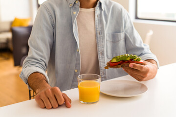 Young mixed race man having breakfast in his kitchen