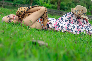 Beautiful portrait Woman, beautiful and strong . Happy and smiling, wearing a hat lying on the green lawn at the ranch with a lot of sensuality.