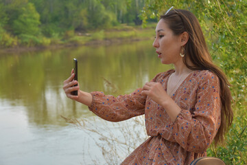 Pretty Asian woman taking selfie in park