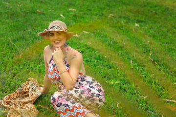Portrait Beautiful and strong woman fighting breast cancer Smiling and a lot of happiness. Bald and in a hat. Willingness to live and joy to fight. Smiling and sitting on the green grass.