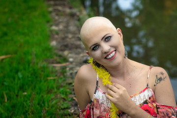 Beautiful and strong bald woman fighting breast cancer Smiling and happy. Hairless. Smiling and looking steady at the pond.