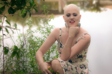 Beautiful and strong woman fighting breast cancer Smiling and happy. Hairless and bald. live and joy of fighting. Flower print dress on the lake and on the ranch.