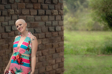 Beautiful and strong woman fighting breast cancer Smiling and happy. Hairless and bald. live and joy of fighting. Sensual dress of flowers in nature. smiling on the wall