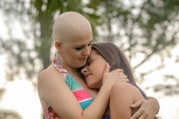 Mature, beautiful and strong woman fights breast cancer disease. Bald man showing new health concept with joy and victorious. Receiving hug from her daughter with a lot of love, affection. Mother and 