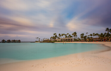 Beautiful vivid sunrise over beach with the villas in the Indian ocean, Maldives. Crossroads Maldives, hard rock hotel, july 2021. Long exposure picture