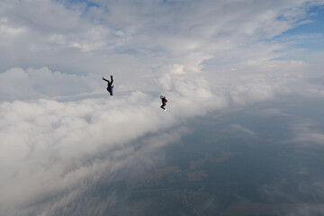 Skydiving. Freefly jump. Two guys are faling in the cloudy sky.