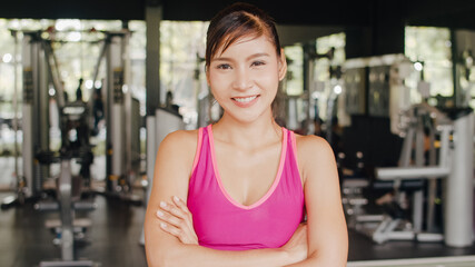 Fototapeta premium Happy Asian healthy sport woman trainer with sportswear smile looking at camera feel cheerful and fresh after workout in gym, People training use in fitness class, sport and healthy lifestyle concept.