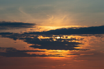 Clouds and atmosphere in warm evening colors with the sun behind the clouds