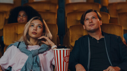 Attractive cheerful young caucasian couple laughing while watching film in movie theater. Lifestyle entertainment concept.
