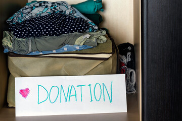 Collecting unnecessary clothes for giving them to charitable organizations to help those in need. Eco-friendly way to get rid of unnecessary things. Concept  donations box, recycle clothes.