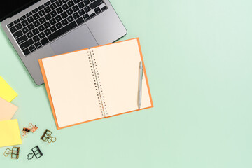 Creative flat lay photo of workspace desk. Top view office desk with laptop, coffee cup and open mockup black notebook on pastel green color background. Top view mock up with copy space photography.