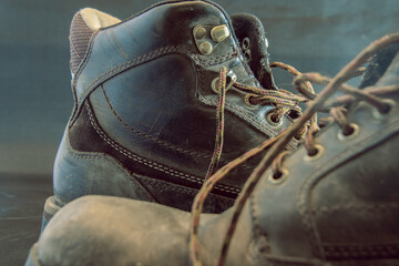 Closeup of dirty and weathered brown work boots on the ground unlaced green and gold colour grading