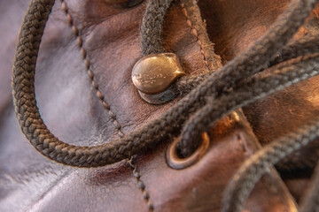 Macro showing details of old brown leather boots showing laces, brass eyelets, grommets and stitching 