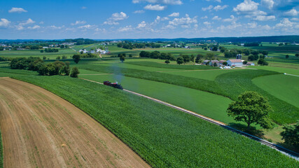 Aerial View of a Steam Locomotive Traveling Across a Fertile Farmland Landscape on a Beautiful Summer Day