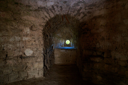 Fortress window, loophole for a cannon in the dark. Architectural medieval background with copy space