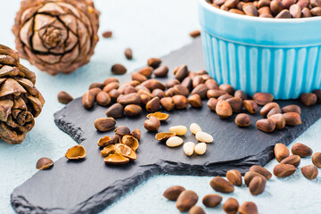 Several peeled pine nuts among in-shell nuts on a slate board. Remedy for insomnia and detox food. Vitamins and health