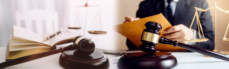 Justice and law concept.Male judge in a courtroom with the gavel, working with, computer and docking keyboard, eyeglasses, on table in morning light