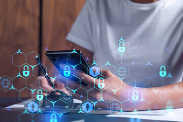A businesswoman in casual wear signing the contract to prevent probability of risks in cyber security. Checking the phone. Padlock Hologram icons over the working desk. Women in business concept.