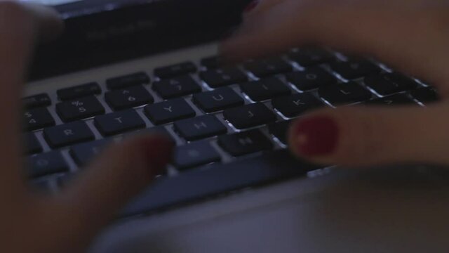 An HD footage of female hands with painted fingernails typing in a laptop keyboard