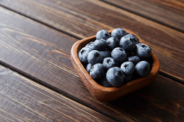 Bowl with fresh blueberries on wooden table