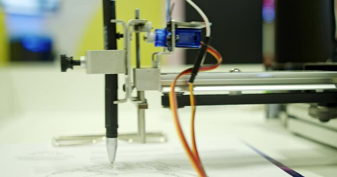 A modern robot draws a picture with a ballpoint pen, modern technologies. the robot is programmed to repeat your handwriting and writes the text with a pen on paper instead of you, as if by hand