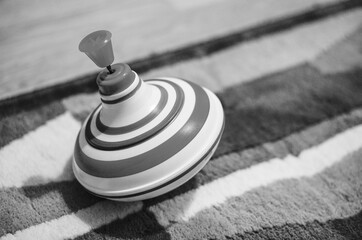 Grayscale shot of a spinning top on a soft carpet