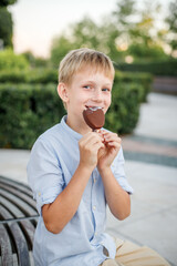 blonde boy in blue shirt eating popsicle ice cream