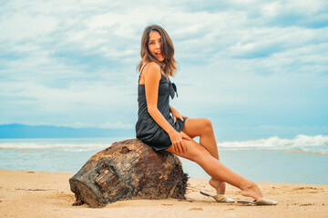 Fototapeta na wymiar happy girl on the beach wearing a black dress
