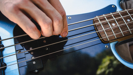 Hands playing bass guitar on open air, playing in a band concept, learning a new instrument concept