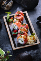 Rolls Kaisen.Rolls with smoked salmon, eel and tuna. Avocado inside rolls.Dark background. Vegetarian food. Traditional Japanese dish.Vertical photo.