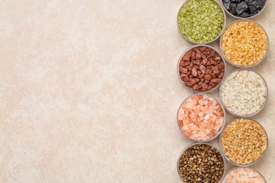 collection of colorful sea salts from different parts of the world, top view on a ceramic background with a copy space