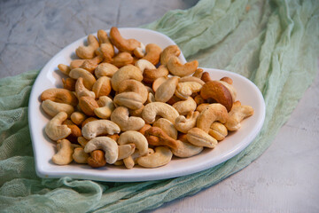 cashew nuts in a plate on a concrete background, heart

